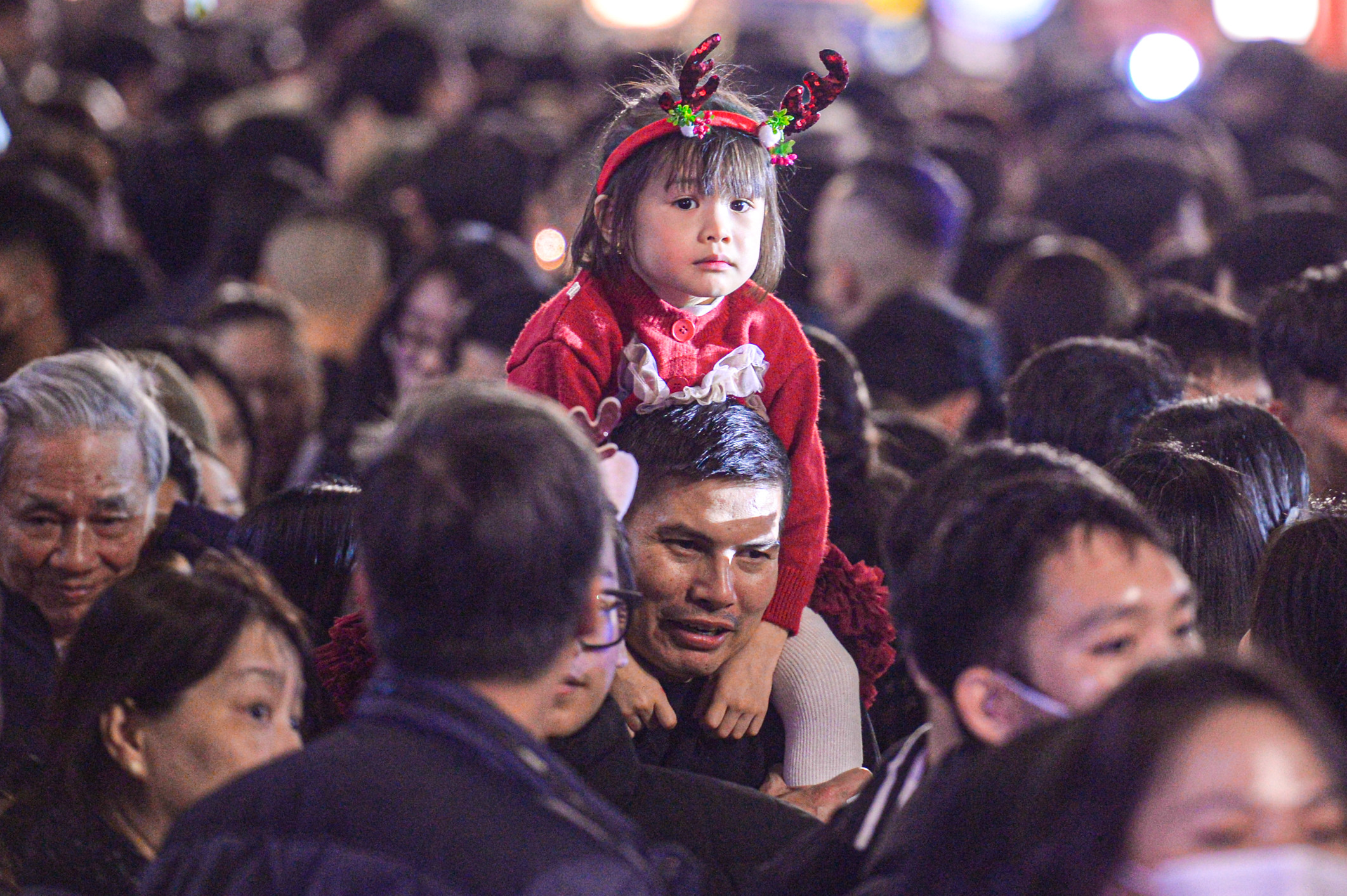 Trẻ nhỏ bơ phờ, ngồi trên lưng bố mẹ vượt biển người đêm Giáng sinh 