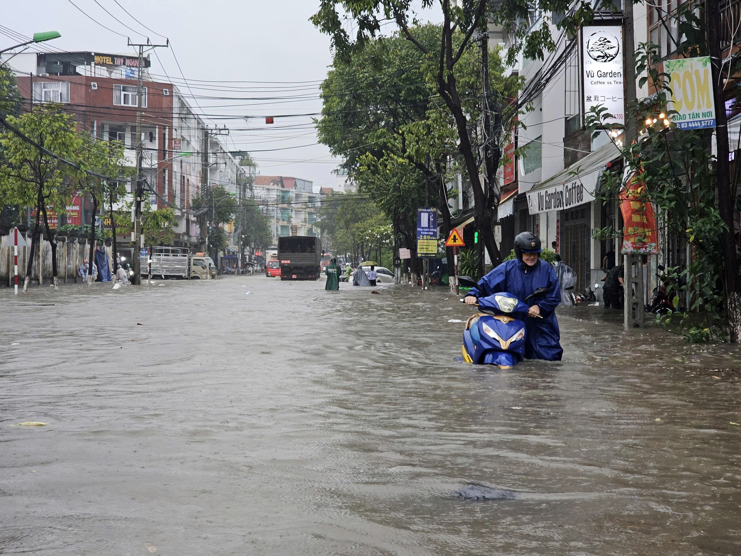Phố biển ngập sau mưa lớn, người dân Nha Trang bì bõm đi làm, cõng con đi học