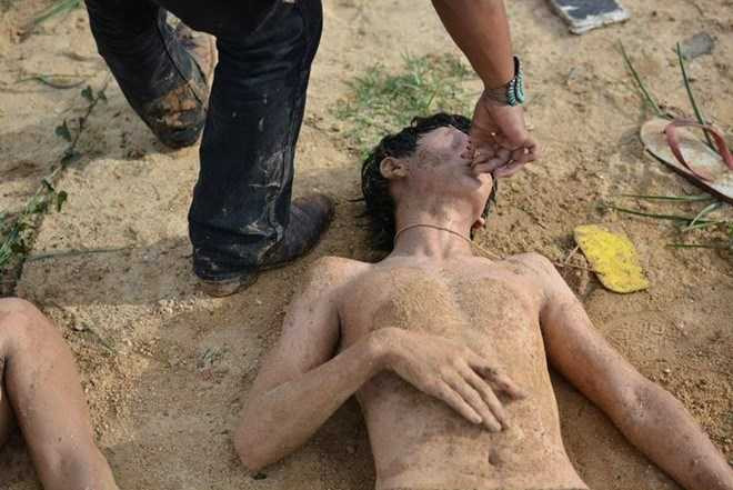 Nam sinh cởi trần bị bịt mũi, phải nằm trên mặt đất bẩn.