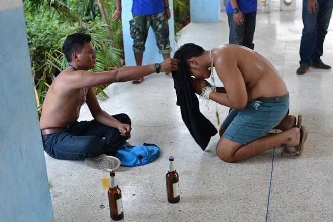 Một đàn em bị trói tay, quỳ lạy đàn anh và phải uống