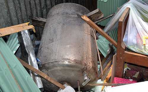 Sức ép từ bình hơi phát nổ hất thùng chứa bột bay xa, rơi thủng mái nhà dân. Ảnh: Thanh Phong 