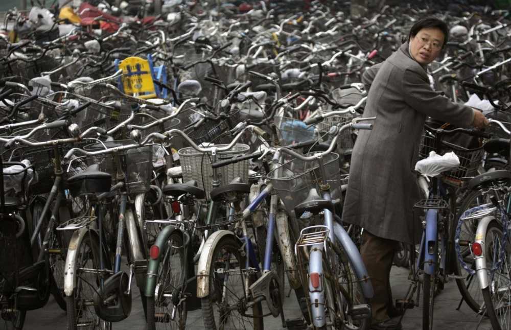 a-woman-collects-her-bicycle-from-a-parking-lot-outside-of-a-subway-station-in-beijing-0110 4