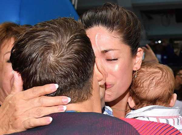 Sau khi đoạt tấm HC vàng 200m bơi bướm hôm 9/8, Michael Phelps tiến tới khán đài nơi vợ con anh đứng để chia vui. Kỷ lục gia Olympic hạnh phúc khóa môi bà xã trong tiếng hò reo của mọi người xung quanh.