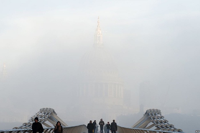 Người đi bộ băng qua Cầu Thiên niên kỷ trước nhà thờ St Paul ở London bị bao phủ trong sương mù