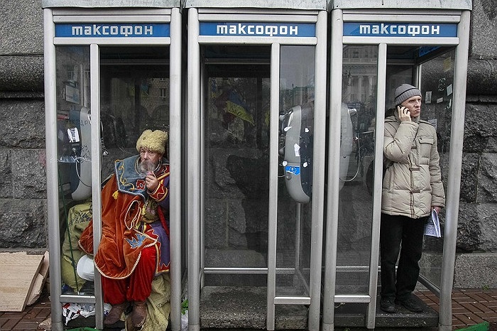 Một người đàn ông mặc đồ truyền thống của Ukraine ngồi hút thuốc trong buồng điện thoại công cộng