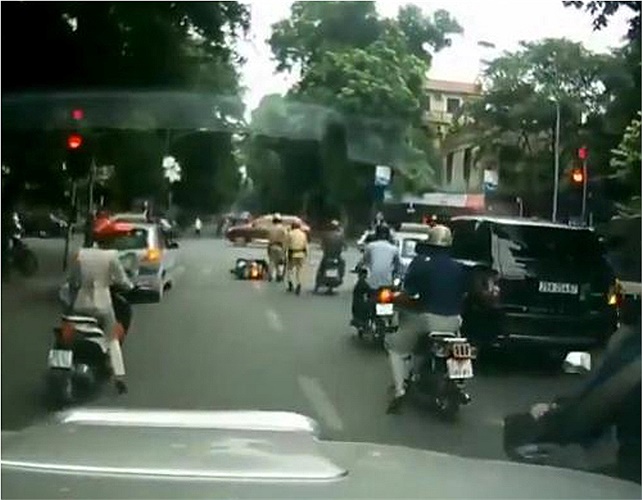 Viên cảnh sát đi cùng nhặt mũ bảo hiểm và lại gần người đi đường bị ngã để xem xét tình hình. Ảnh cắt từ video trên Youtube.