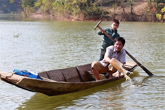 Em Đạt đi học về được bố đón, hai bố con thay nhau chèo, tát nước ra khỏi thuyền. 