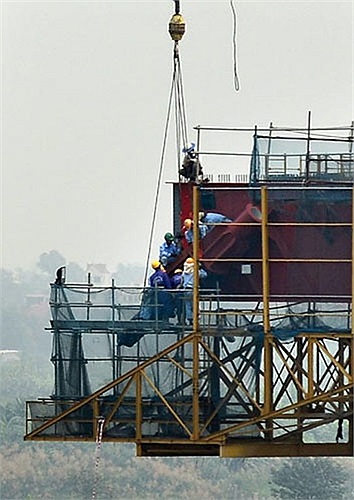 Các công nhân làm việc trên mép nối giữa hai trụ tháp với những thiết bị khổng lồ. 