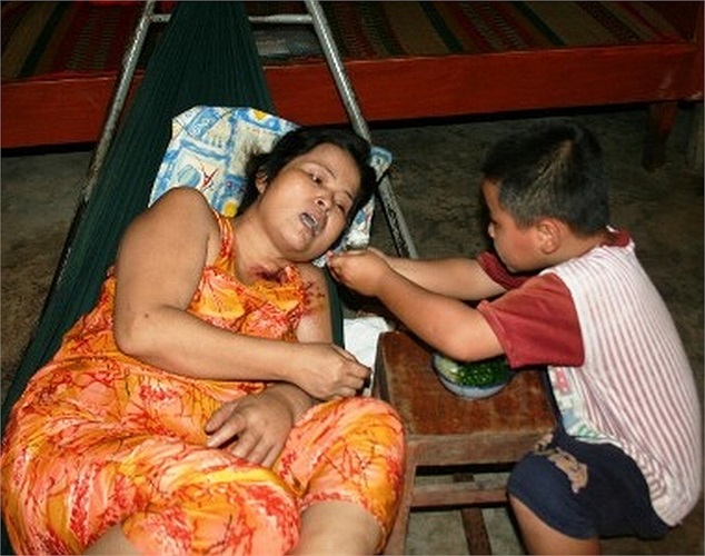 Bé Mai Xuân Trường, chưa tròn 5 tuổi đang đút từng thìa cơm cho người mẹ nằm thoi thóp trên chiếc võng cũ. 