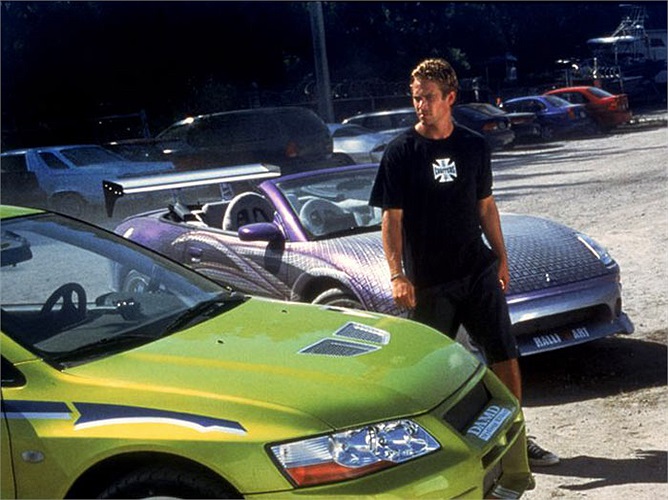 Paul Walker đứng giữa chiếc Mitsubishi EVO 7 và chiếc Mitsubishi Eclipse Spyder trong một cảnh phim của Fast and Furious 2.