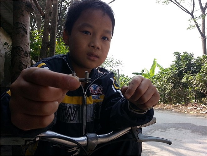 Cậu nhóc Tuấn đang chỉ mắt xích bị tuột ra không đi được và nhờ ông Tâm sửa hộ để thứ hai có xe đi học. 