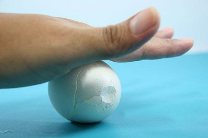 Tiếp theo, bạn đặt quả trứng nằm ngang, ấn tay và lăn trứng về phía trước cho vỏ nứt ra. 