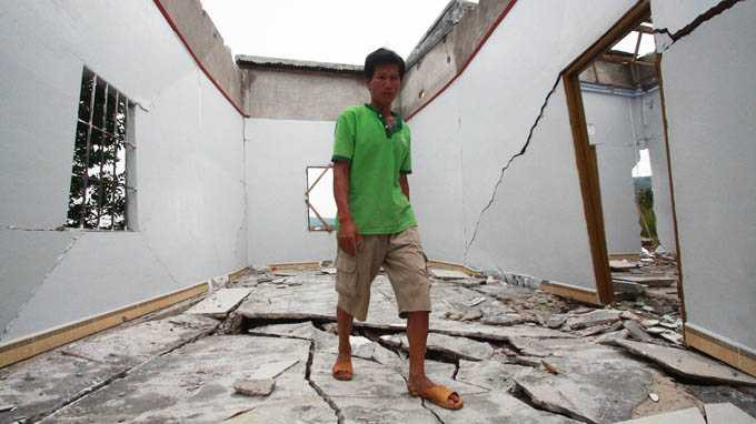Ông Dương Văn Sản dọn dẹp những khối bê tông đổ sập ngay tại căn nhà chưa kịp xây xong của mình vào chiều 13-10.