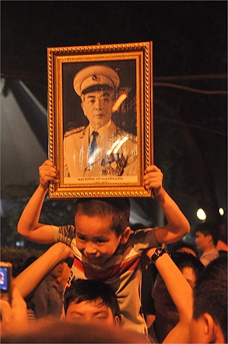 Một em bé giương cao di ảnh Đại tướng giữa dòng người đông đúc.