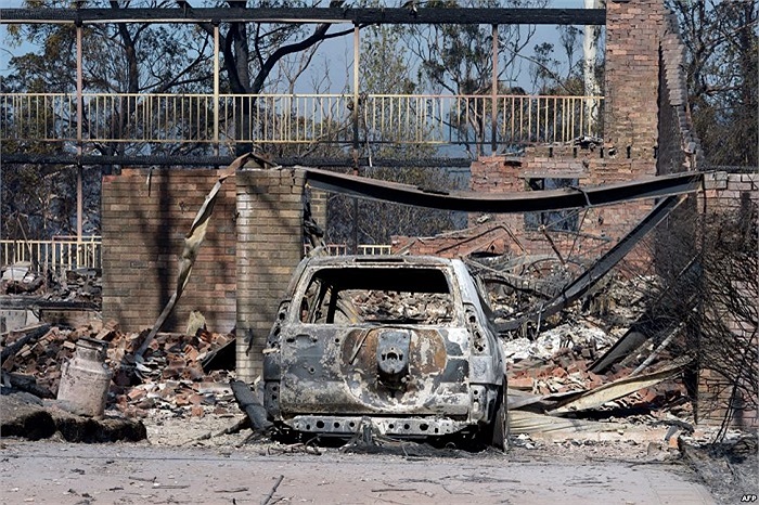 Chiếc xe bị cháy trước một ngôi nhà chịu ảnh hưởng của vụ cháy rừng ở Winmalee, Sydney, Australia