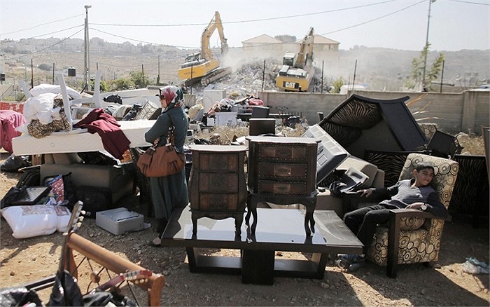 Một người phụ nữ Palestine đứng gần đồ đạc trong nhà khi căn hộ của cô bị phá hủy