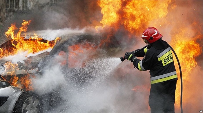 Lính cứu hỏa đang phun nước vào chiếc xe bốc cháy trên đường dẫn tới sân bay ở Warsaw, Ba Lan, chưa rõ nguyên nhân gây ra vụ cháy