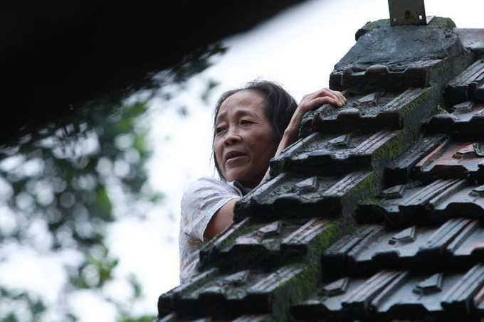 Bà Đặng Thị Hương phải nhoài người từ nóc nhà để nói chuyện với phóng viên do nhà bị ngập