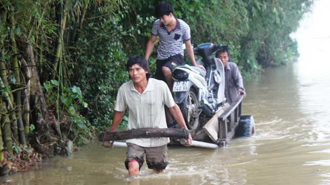 Người dân vận chuyển xe máy ra khỏi nơi ngập lụt