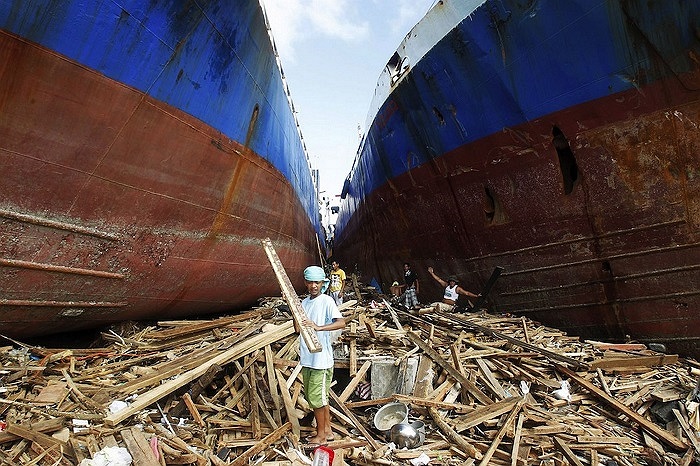 Người dân đang nhặt gỗ giữa hai con tàu trôi dạt sau bão tại thành phố Tacloban