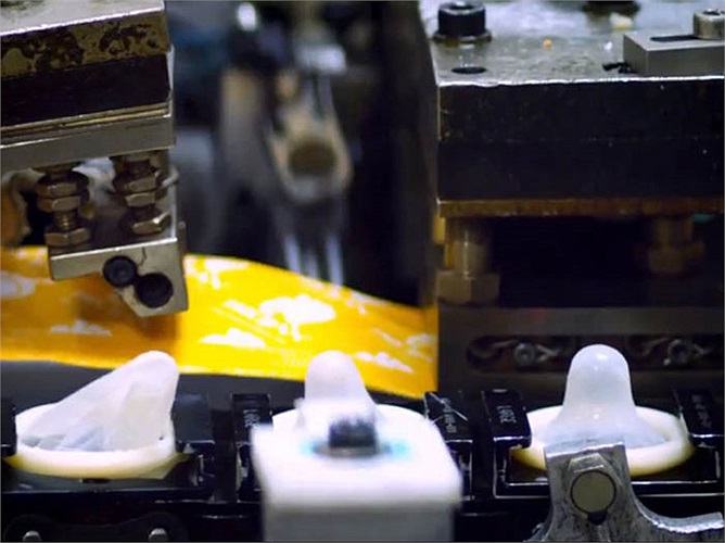 Bao cao su gần như đang ở giai đoạn cuối dây chuyền lắp ráp. Chúng được đặt trong vỏ bao nhựa in nhãn thương hiệu Trojan.