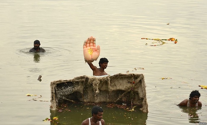 Một người giơ bàn tay một tượng thần voi Ganesh của Ấn Độ giáo, vị thần của sự phồn thịnh, trong buổi lễ nhúng tượng xuống nước ở hồ Hussain Sagar tại thành phố Hyderabad ở miền nam Ấn Độ