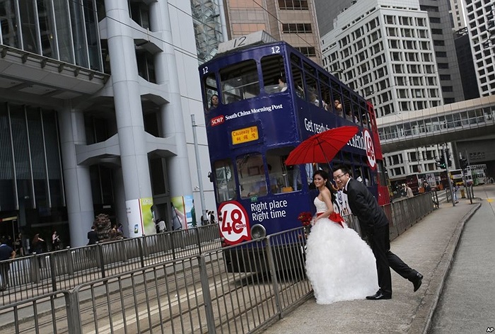 Cặp vợ chồng đứng chụp hình đám cưới gần xe điện tại trung tâm Hongkong