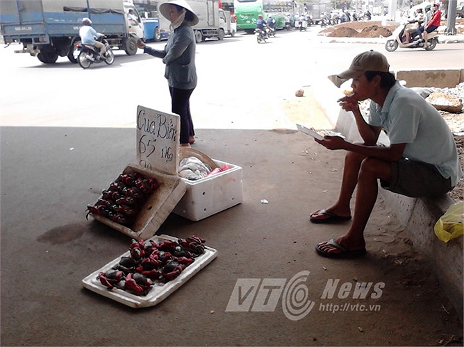 Người đàn ông ăn vội hộp cơm trưa, người phụ nữ vẫy tay mời đón khách đi đường ghé mua cua dưới chân cầu vượt Kha Vạn Cân (Q.Thủ Đức). 