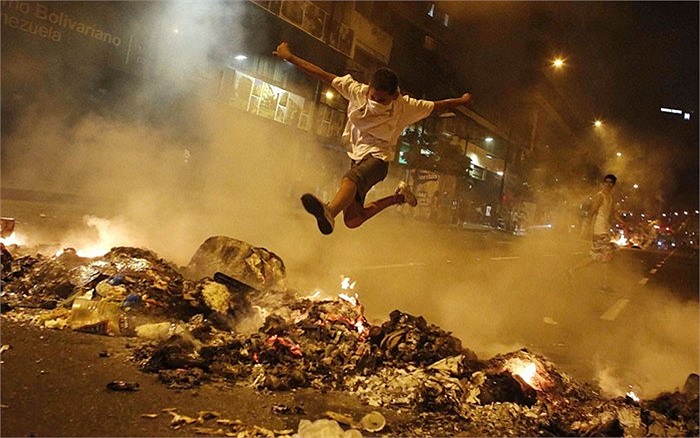 Cậu bé nhảy qua đống rác ở Caracas, Venezuela