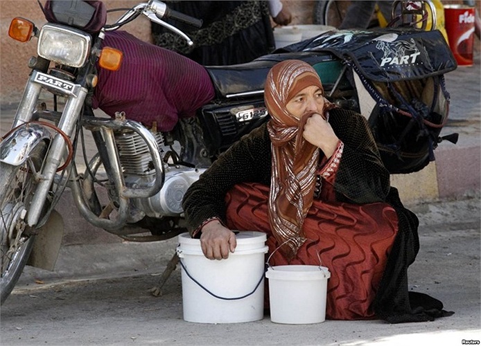 Người phụ nữ ngồi chờ đến lượt mình nhận phần ăn miễn phí ở thành phố Raqqa, phía đông Syria