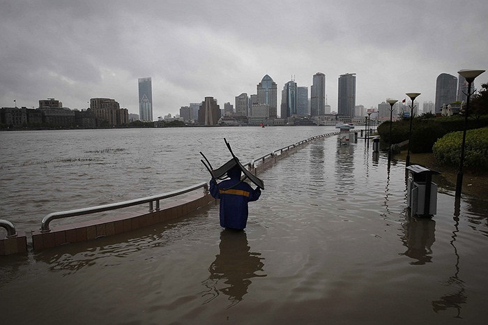 Người dân mang chiếc ghế qua vùng nước ngập ở Thượng Hải, Trung Quốc
