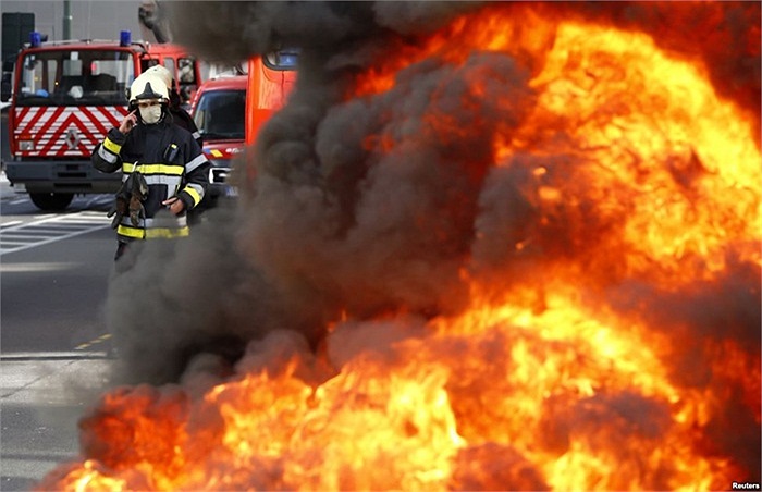 Lính cứu hỏa người Bỉ đứng sau đống lốp xe bốc cháy trong cuộc biểu tình của lính cứu hỏa đòi điều kiện làm việc tốt hơn ở trung tâm thủ đô Brussels