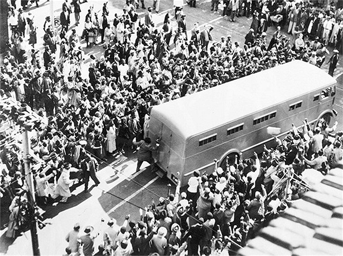 Đám đông vây quanh xe cảnh sát chở ông Nelson đến tòa án để luận tội 'phản quốc' năm 1956