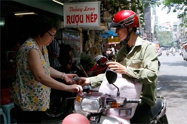 Một người xe ôm tranh thủ ghé qua mua ít rượu nếp về ăn Tết 'diệt sâu bọ'. (Ảnh: PetroTimes)