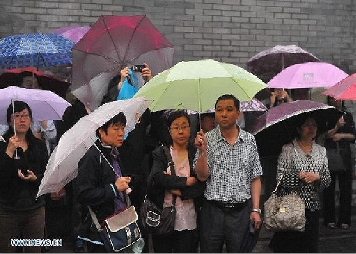 Cha mẹ đợi dưới mưa trong khi con cái đang thi bên trong.