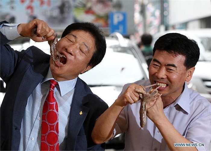 Hai người đàn ông có vẻ thích thú khi tham gia cuộc thi ăn bạch tuộc sống hôm 12/9