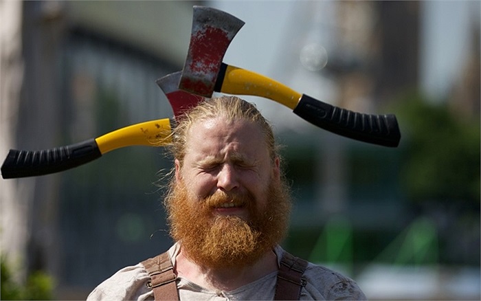 Nghệ sĩ xiếc người Canada, Matias Salmenaho, đứng im trong khi bạn diễn ném 2 chiếc rìu qua đầu