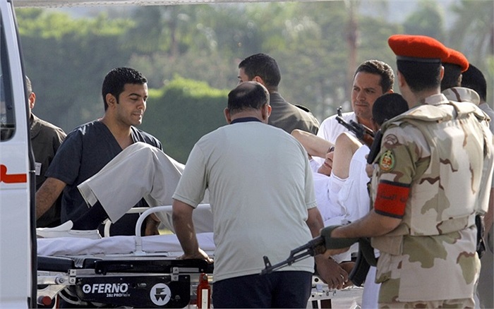 Nhân viên y tế và cảnh sát hộ tống cựu Tổng thống Hosni Mubarak của Ai Cập lên xe cứu thương đến bệnh viên sau khi ông được trả tự do 
