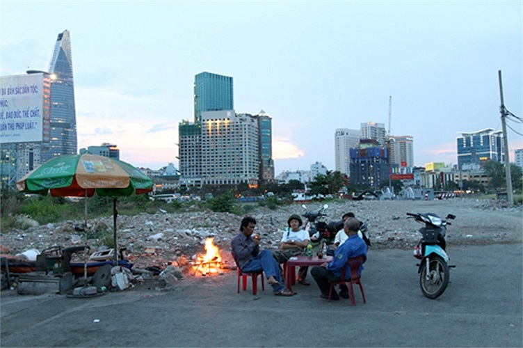 Khi thành phố sắp lên đèn, bốn người lái xe ôm tại cổng bến phà Thủ Thiêm cũ đang đốt lửa để đuổi muỗi. Họ đã bám trụ ở đây nhiều năm, từ khi quận 2 chưa giải tỏa phục vụ dự án khu đô thị Thủ Thiêm. (Theo VNE)