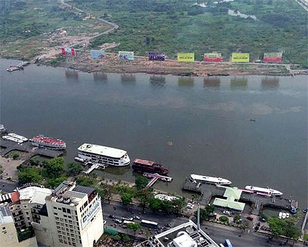 Sau ba năm triển khai, khu đô thị mới Thủ Thiêm (quận 2) vẫn giậm chân tại chỗ khiến khu đất giải tỏa trở nên hoang vắng với cây cỏ mọc ùm tùm, gạch ngói ngổn ngang. Còn bên này bờ (quận 1) là những cao ốc san sát cùng tàu thuyền và phố xá nhộn nhịp.