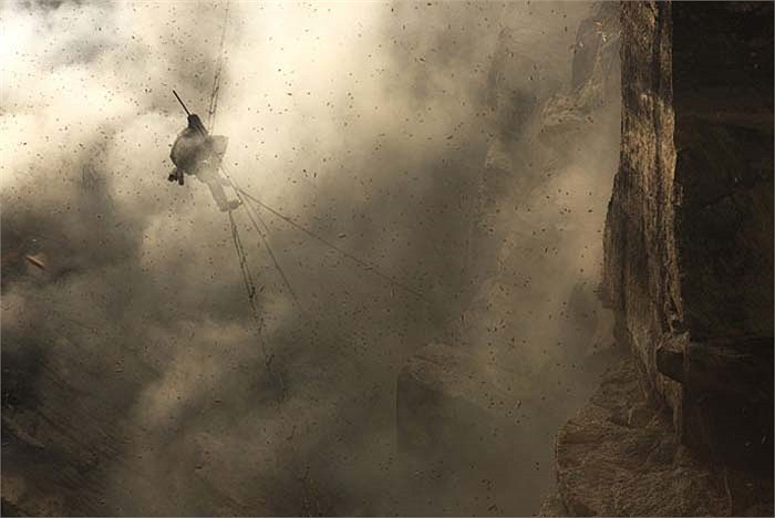 Người đàn ông này đang khéo léo dùng một cây gậy nhỏ để tách tảng sáp ong khổng lồ ra khỏi vách đá.