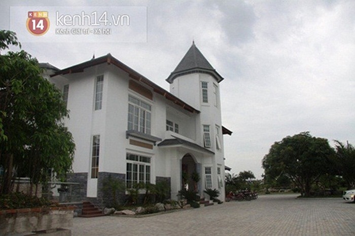 Toàn cảnh ngôi biệt thự và không gian xung quanh, với rất nhiều cây xanh và một hồ nước rộng lớn.