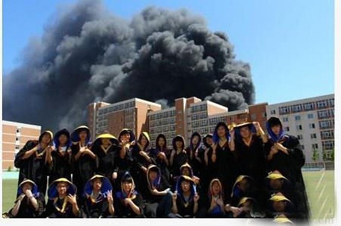 Chụp ảnh kỷ niệm trước một khu nhà đang cháy.