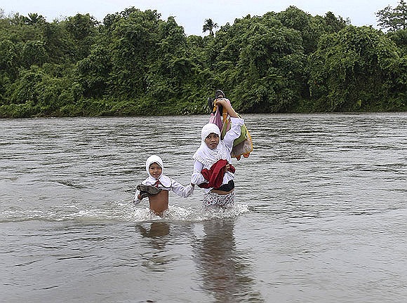 Các học sinh thuộc 46 gia đình trong một ngôi làng tại Indonesia lội qua sông đi học