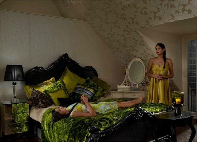 Một cô con gái đang nằm trải dài trên giường dưới sự quản lý gắt gao của bà mẹ.