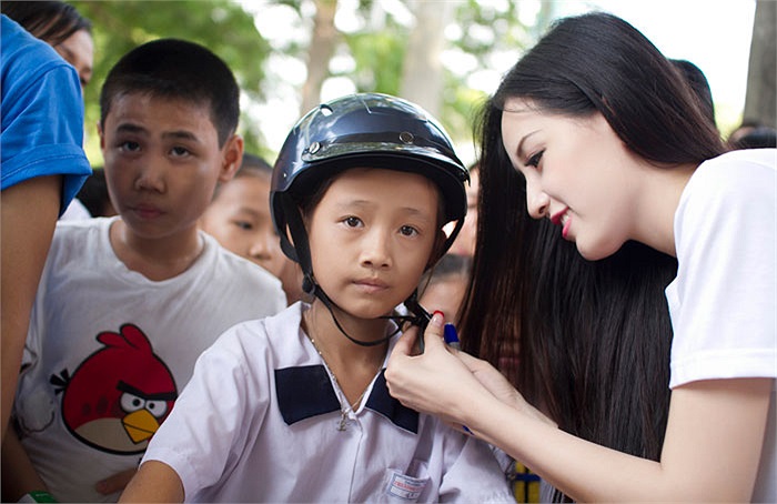 Cô cẩn thận cài mũ bảo hiểm cho một bé trai.