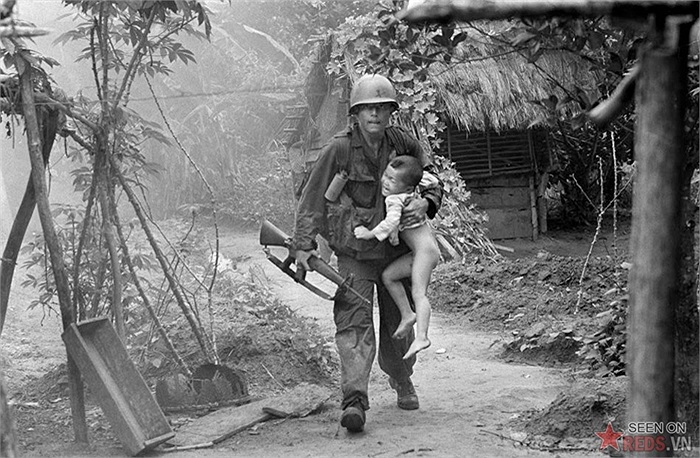 Lính Mỹ thuộc đại đội A, tiểu đoàn 1, sư đoàn bộ binh số 16 mang một đứa trẻ đang khóc từ làng Cam Xe sau khi ném một lựu đạn cháy vào một công sự trong chiến dịch gần khu trồng cao su Michelin, Tây Bắc Sài Gòn
