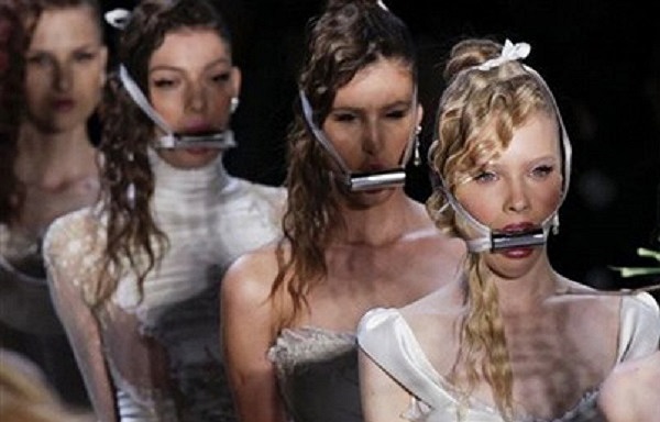 Trong những trang phục dạ hội và áo cưới sang trọng, tay người mẫu bị trói quặt ra đằng sau bằng những dải truy băng, các phụ kiện như hoa, ví, túi xách… sẽ được các người mẫu ngậm trên miệng.