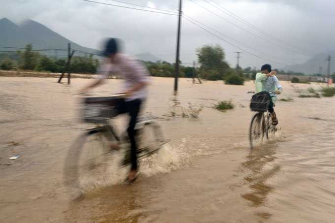 Học sinh đi học về bất chấp nguy hiểm vượt qua đoạn đường ngập lũ ở xã Quế Trung, huyện Nông Sơn. Ảnh: Lê Trung