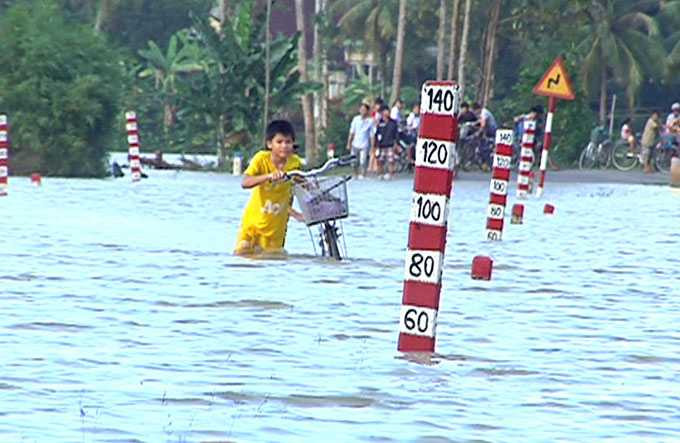 Bất chấp nguy hiểm, người dân, trẻ em ở huyện Bình Sơn (Quảng Ngãi) vẫn băng qua đường lũ tràn